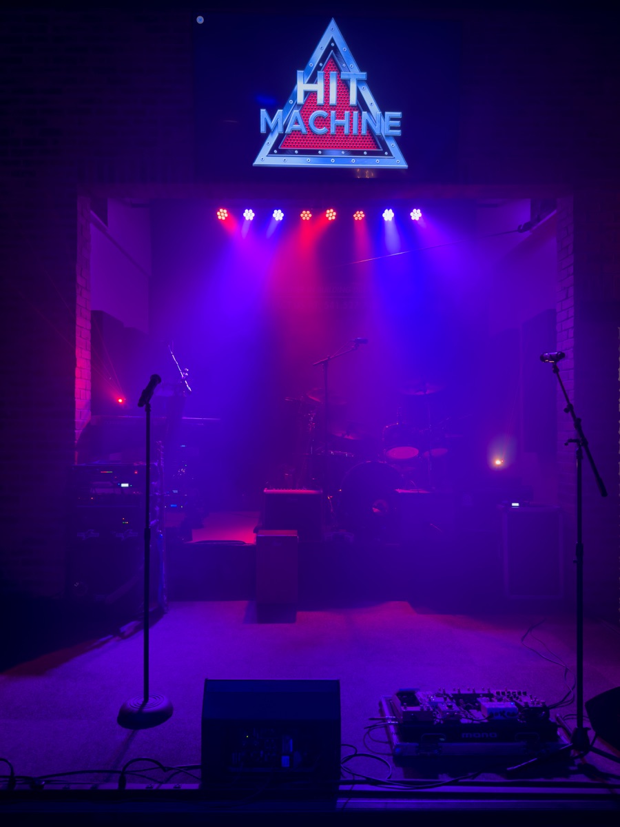 Hit Machine band on stage surrounded by lights and hands in the air